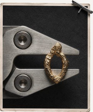 A gold ring held in flat-nose pliers at the bench
